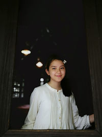 Portrait of smiling girl standing at window