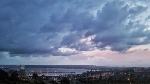 Aerial view of city by sea against storm clouds