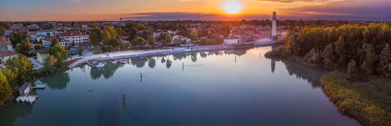 High angle view of river by buildings against sky during sunset