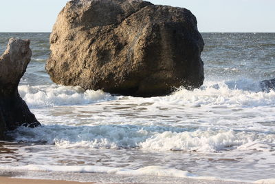 Rock formation in sea against clear sky