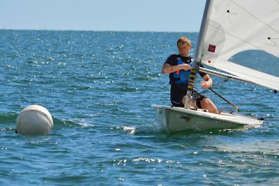 Man sailing on sailboat in sea during race