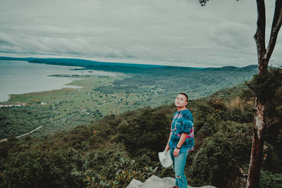 Portrait of smiling woman standing on mountain against sky