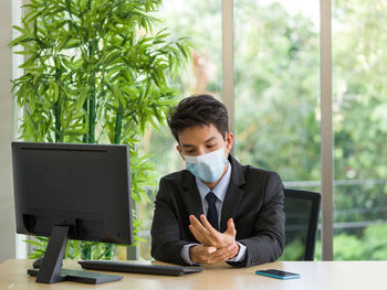 Young businessman sitting on table in office