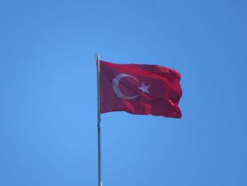 Low angle view of flag against blue sky