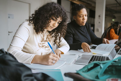 Multiracial female students studying while sitting at table in community college