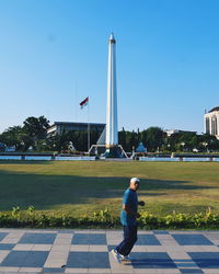 Full length of man and flag against clear blue sky