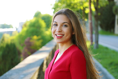 Portrait of smiling young woman standing on footpath