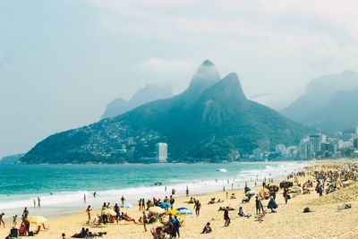 People at beach against mountains during foggy weather