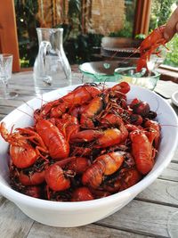 High angle close-up of crayfish in bowl served on wooden table