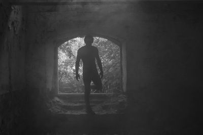 Rear view of silhouette man standing in tunnel