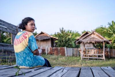 Woman, girl, sitting on a lonely park wooden bridge