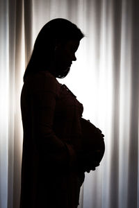 Side view of silhouette woman standing against window