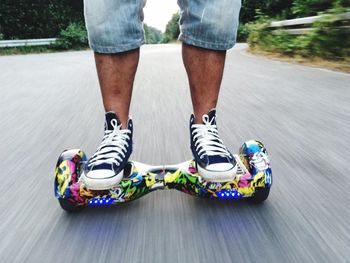 Low section of man riding self-balancing scooter on road