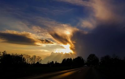 Road passing through landscape against cloudy sky