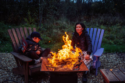 Woman and boy sitting against fire