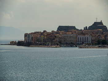 Buildings by sea against sky