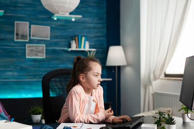 Girl looking away while sitting on table at home