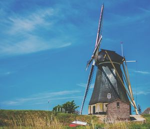 Traditional windmill on field against blue sky