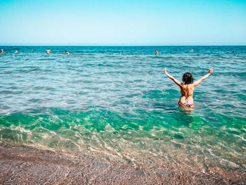 Rear view of woman standing in sea against clear sky