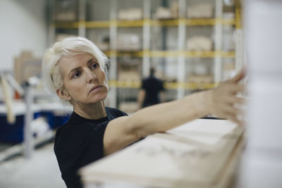 Serious woman examining wooden planks in industry