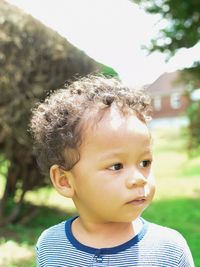 Close-up of thoughtful boy standing in yard
