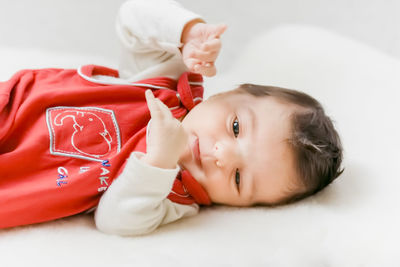 Close-up of cute baby relaxing on bed at home