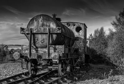 Abandoned train on field against sky