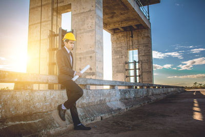 Full length of thoughtful architect standing at construction site during sunset