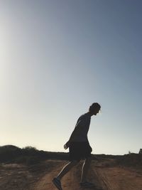 Side view of man standing on field against clear sky