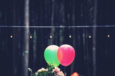 Close-up of multi colored flowers bouquet and balloons against trees