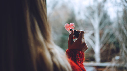 Rear view of woman drawing heart shape on glass