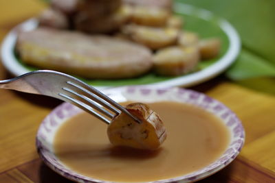 Grilled banana with dipping sauce on wooden table.