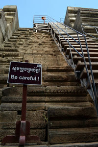 Low angle view of information sign on staircase against sky