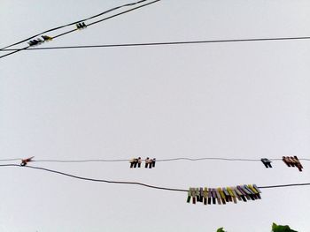 Low angle view of men hanging on rope against clear sky