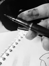 Close-up of messy hand holding pen on table