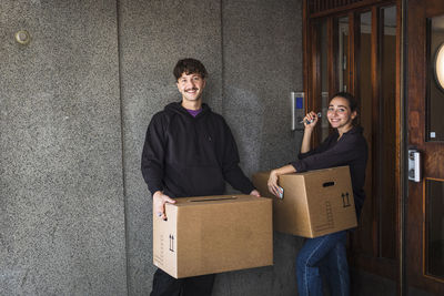 Smiling couple carrying boxes and holding keys