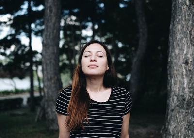 Woman with closed eyes against trees