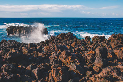 Scenic view of rocks in sea against sky