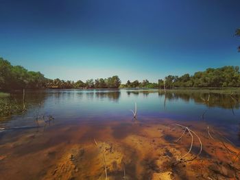 Scenic view of lake against clear blue sky