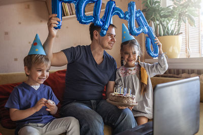 Cheerful father holding cake sitting with kids