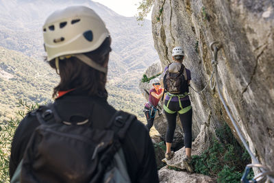 Concept: adventure. two women and a man in the mountains with a helmet, harness, backpack and equipment for the via ferrata.