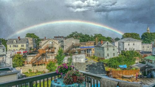 Rainbow over city against cloudy sky