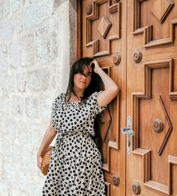 Young woman standing against door