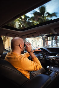Bald bearded middle-aged man drives a car