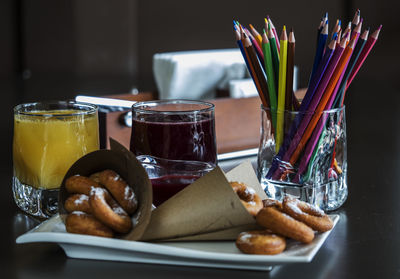 Close-up of food and drink by colored pencils in tray on table