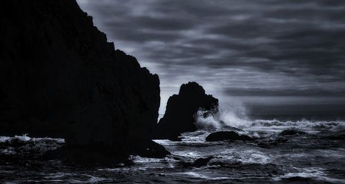 Rock formation in sea against sky