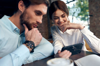 Cheerful colleagues looking at mobile phone