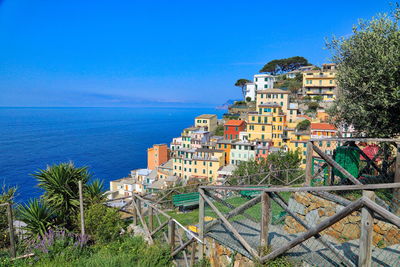 Buildings by sea against clear blue sky