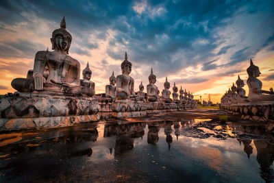 Statue of ancient buddha statues against sky during sunset