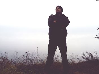 Man standing by tree against sky